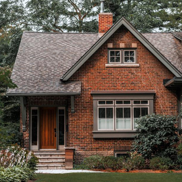 Close up of a red brick home with trees surrounding it.